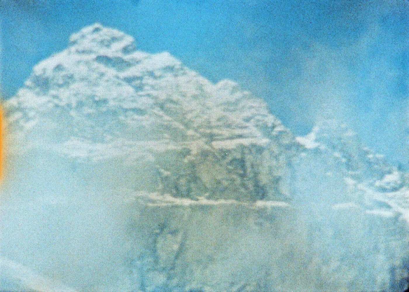 Filmstill aus Mount Supernal: verschneiter Berggipfel doppelt belichtet vor hellblauem Himmel