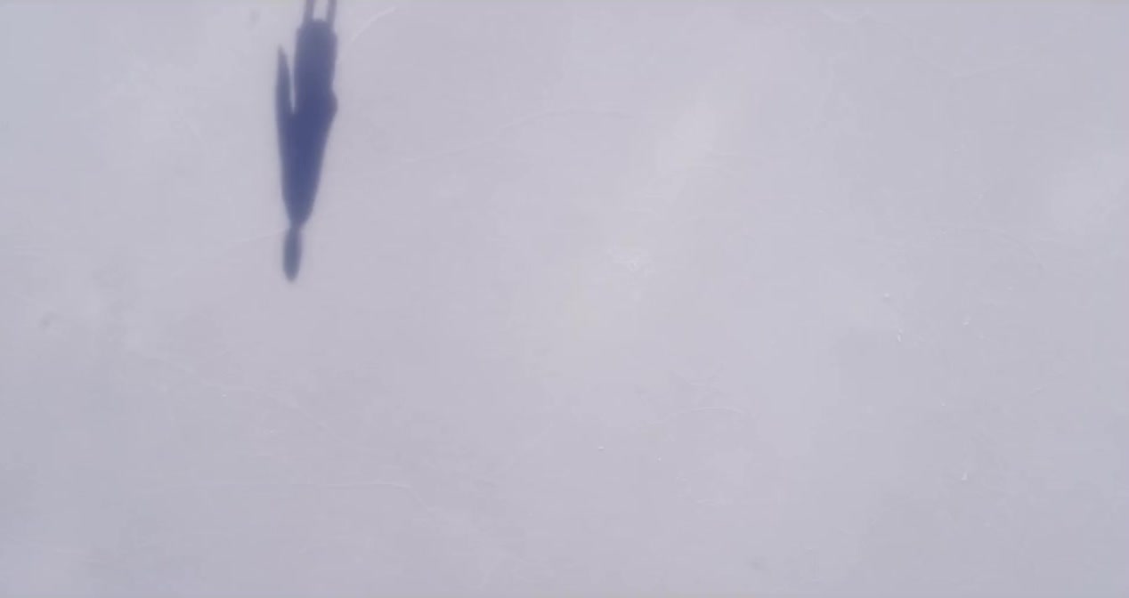 Filmstill aus UBS Winter Screens: Figur mit langem Schatten im Schnee, von oben
