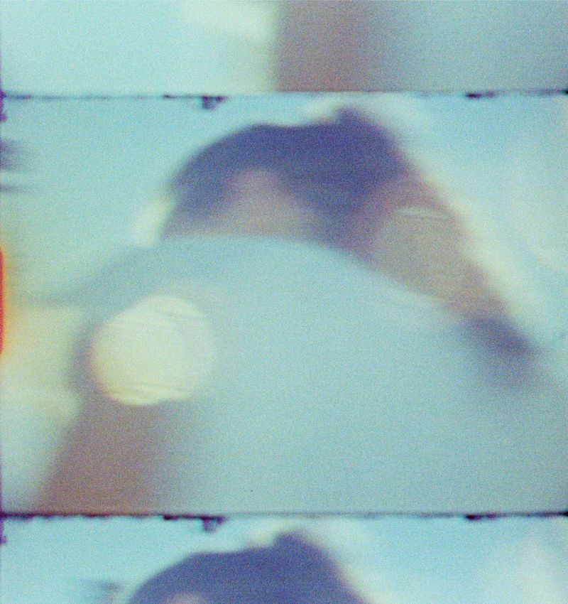 Fine Art Print: Verschwommenes Gesicht vor Türkis, Lichtpunkte, Filmkanten